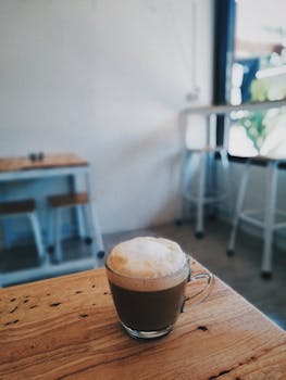 在一家舒适的咖啡馆里，一杯起泡的卡布奇诺放在质朴的木桌上