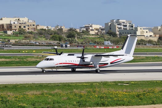 A turboprop airplane taxis on the runway with urban buildings in the background.