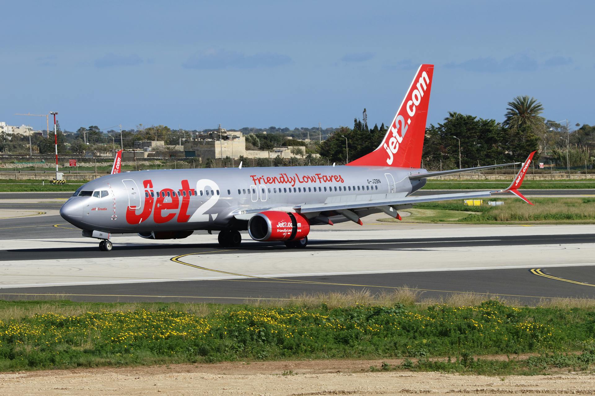 Jet2 airplane on airport tarmac with clear blue sky, showcasing travel and transportation.