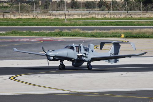 Free Twin-engine aircraft taxiing on airport runway with pilot visible inside cockpit. Stock Photo