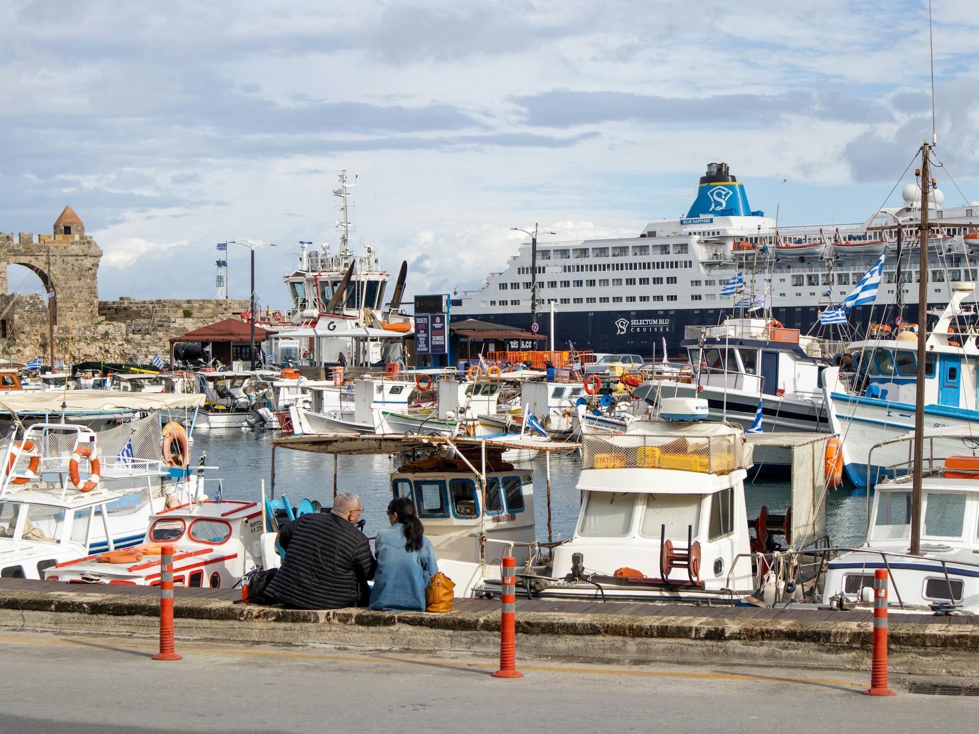 A vibrant harbor scene featuring a cruise ship and various boats docked at a sunny waterfront.