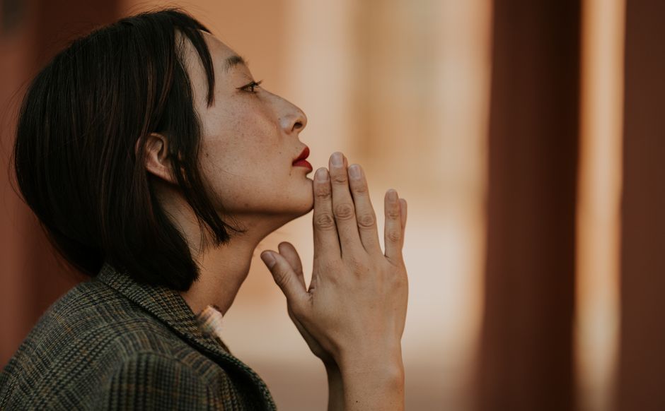 手を握り、思索にふける女性の横顔。