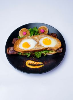 Playful breakfast plate featuring eggs fried in bread with decorative garnishes.