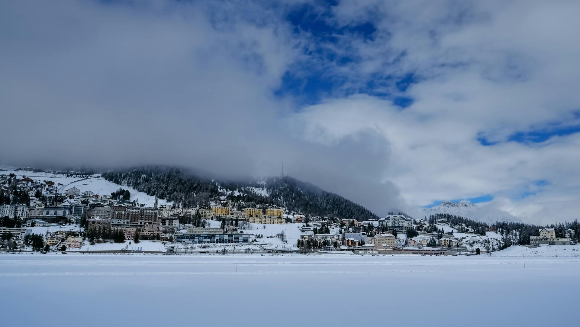 Snowy alpine town landscape with blue sky and clouds, perfect for winter travel themes.