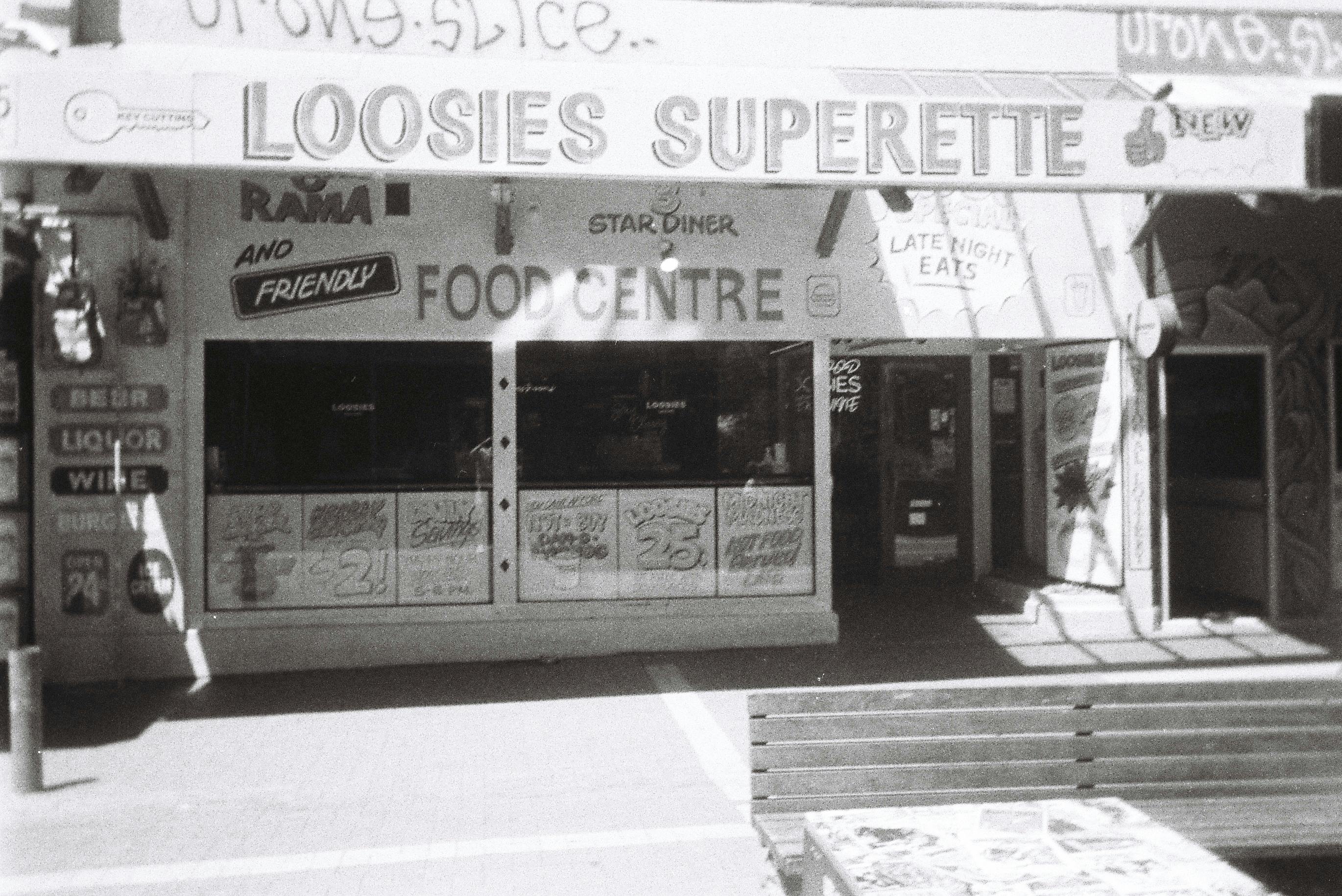 Black and white photo of Loosies Superette in Wellington, reflecting vintage urban charm.