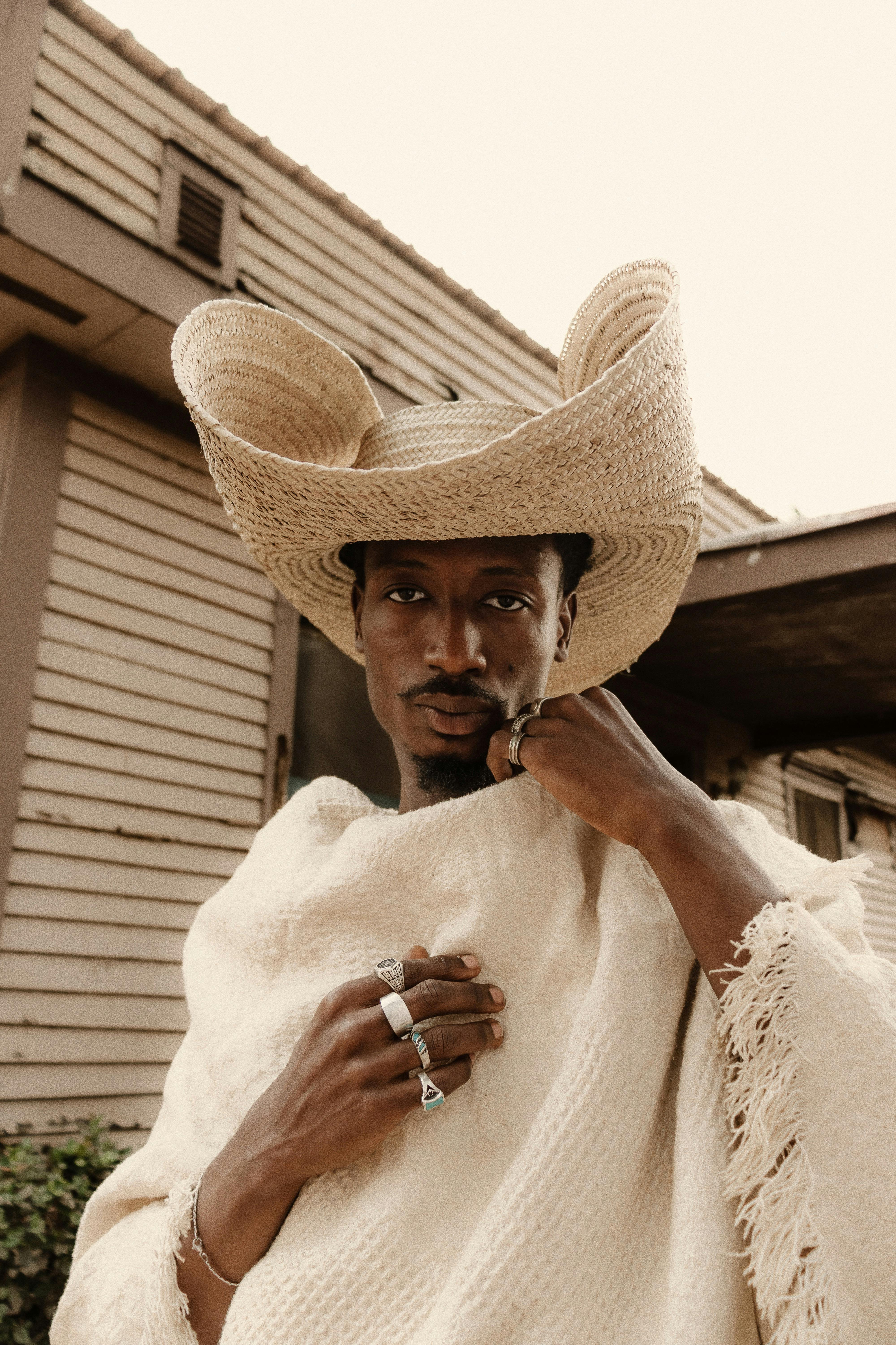 Man in stylish traditional attire and cowboy hat in Abuja, Nigeria, showcasing cultural fusion.