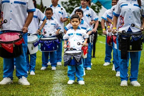 Free Children in a marching band uniform playing drums on a grassy field. Stock Photo