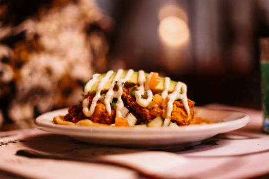 Delicious gourmet dish with fresh toppings and creamy dressing served on a white plate.