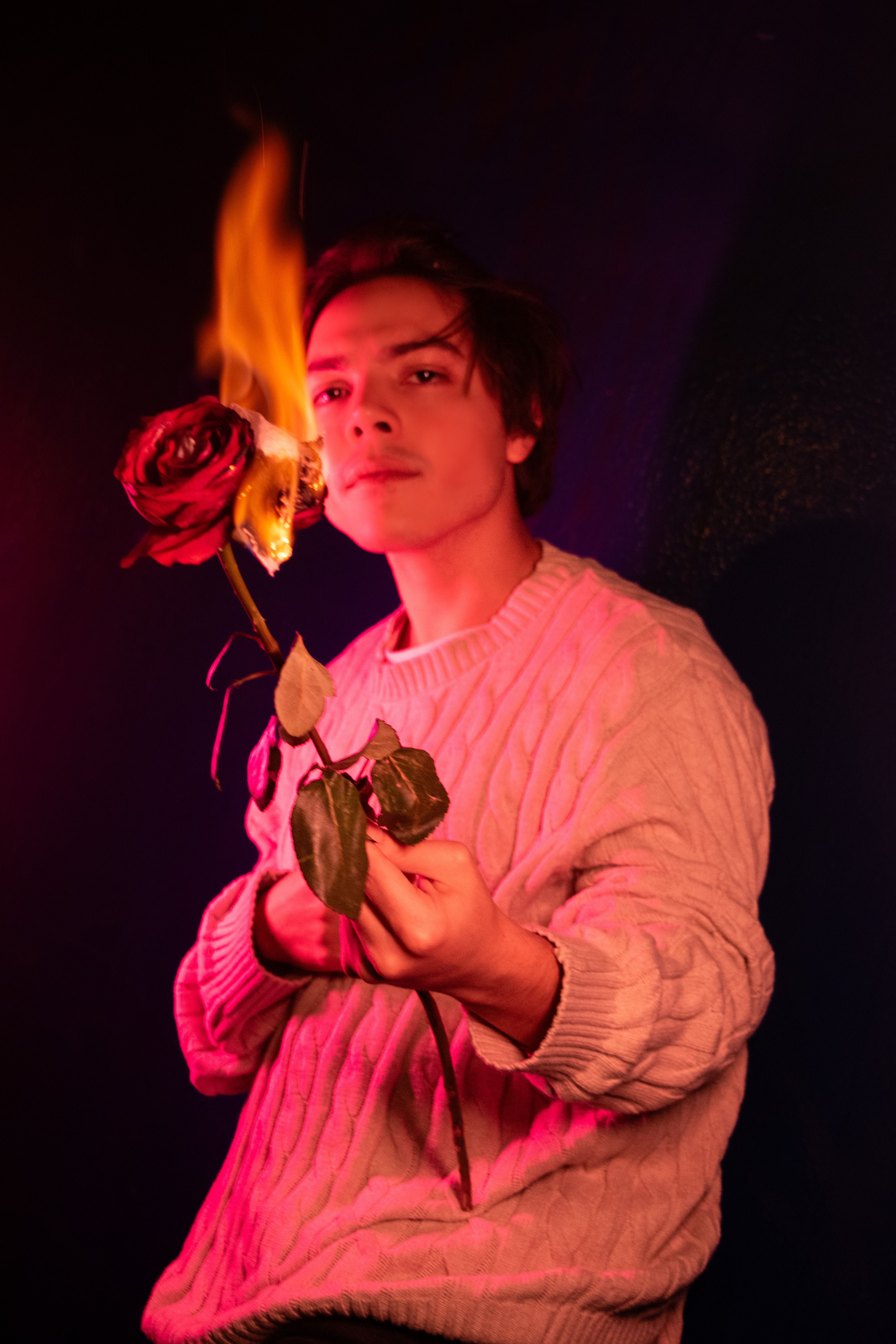 A dramatic portrait of a person holding a flaming rose, with a moody and artistic tone.