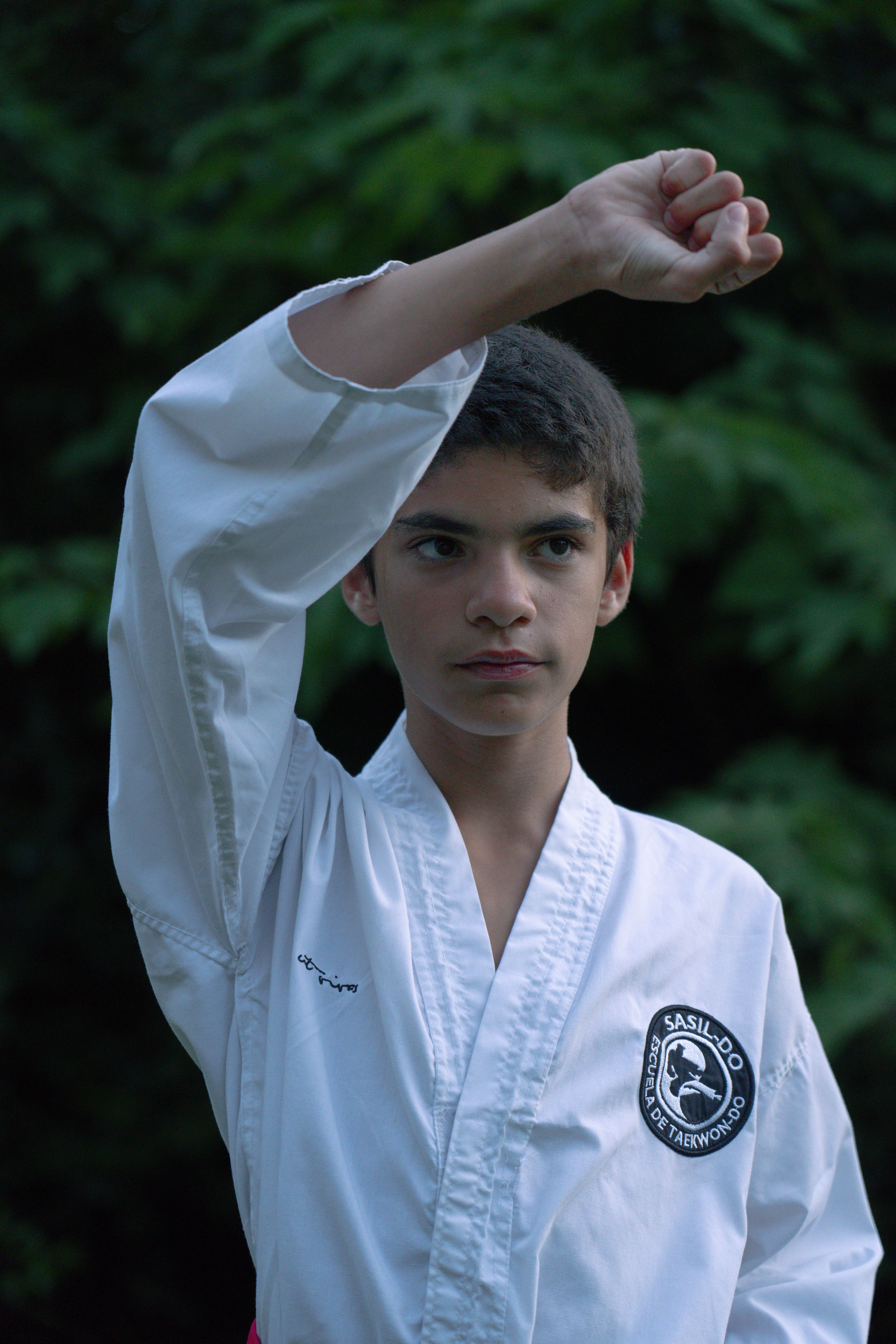 Teenager in martial arts uniform practicing outdoors, showcasing Taekwondo skills.