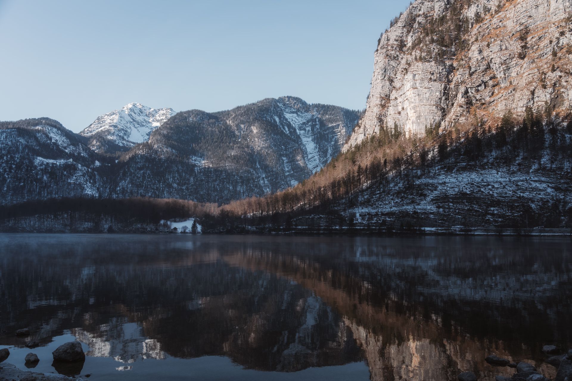 Breathtaking winter view of the Austrian Alps with mountain reflections on a tranquil lake.