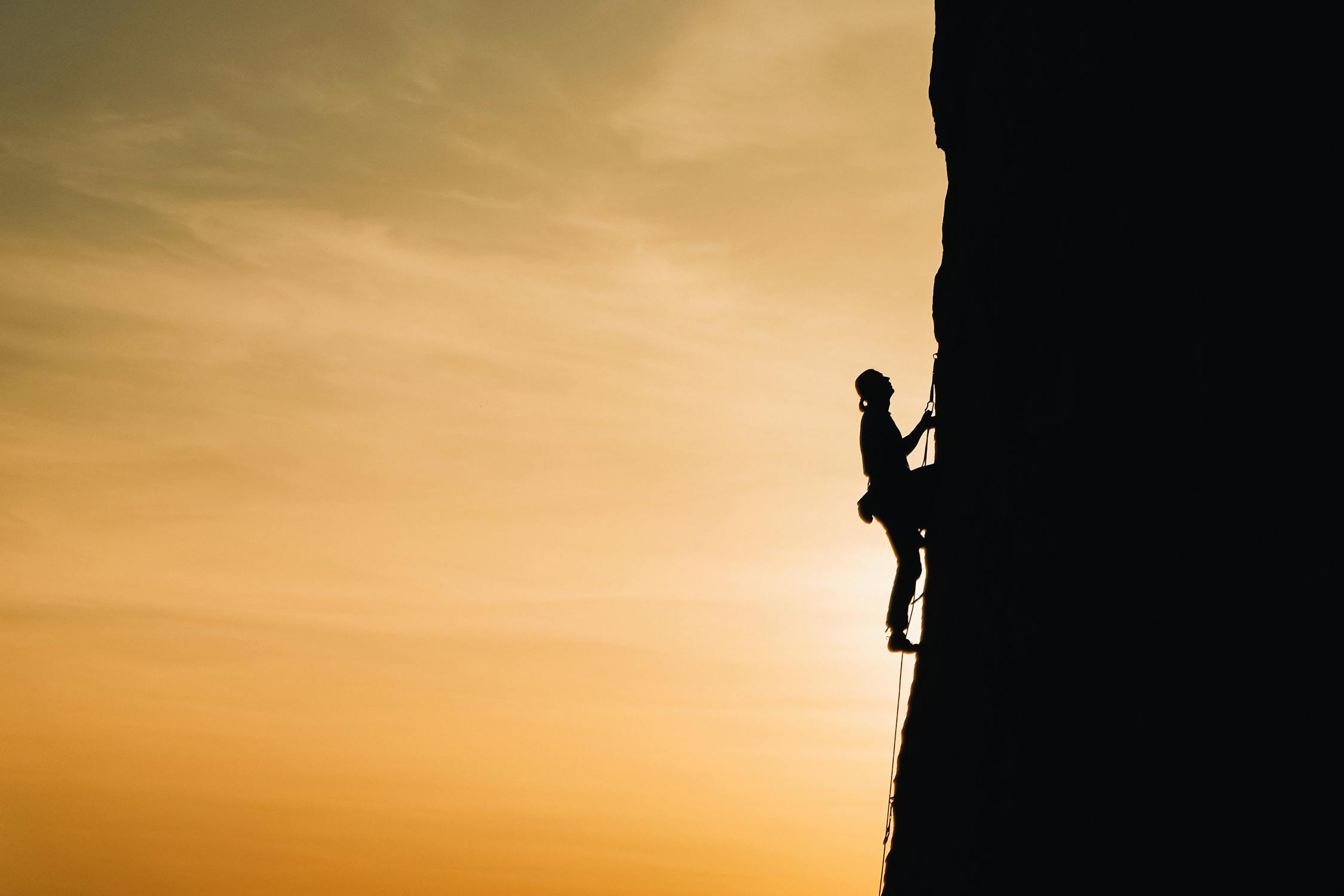 Person rock climbing during sunset, a metaphor for customer's expending a lot of effort 