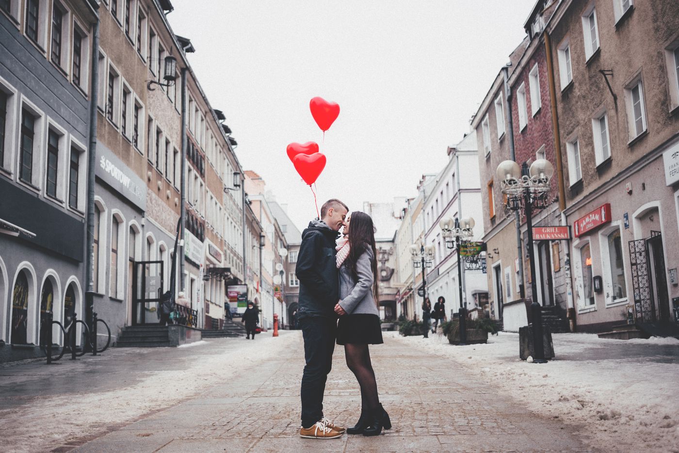 Pareja besándose en plena calle con globos de corazón