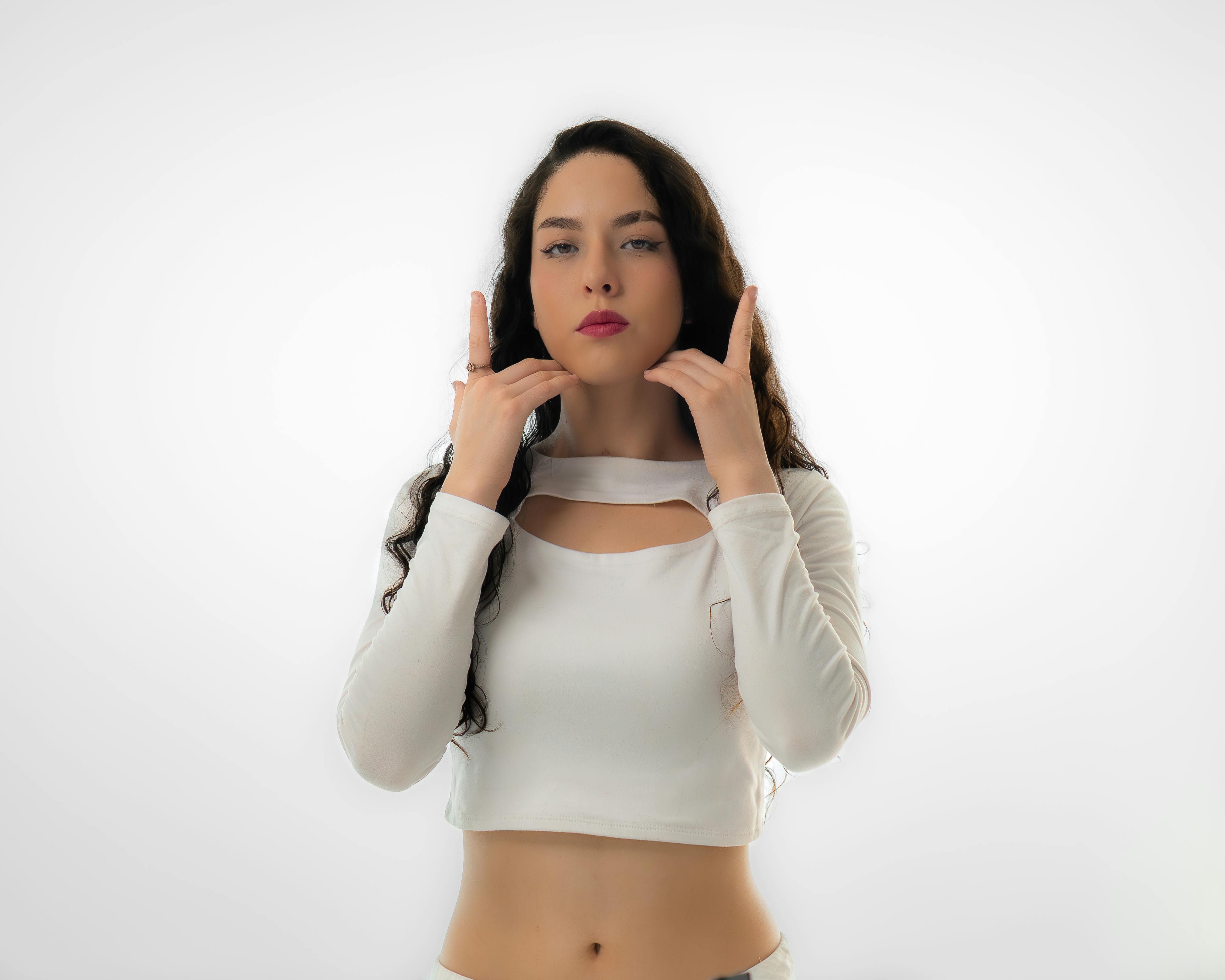 Miễn phí Người phụ nữ thanh lịch tạo dáng tự tin trong trang phục trắng thời trang, thể hiện sự quyền lực và điềm tĩnh. Ảnh lưu trữ