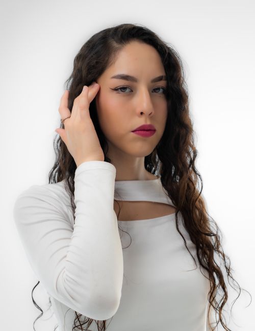 Free Stunning portrait of a young woman in a white dress with curly hair against a white background. Stock Photo