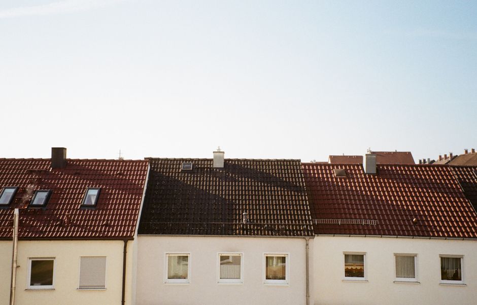 Beautiful red and brown tiled rooftops under clear blue sky in suburban area.