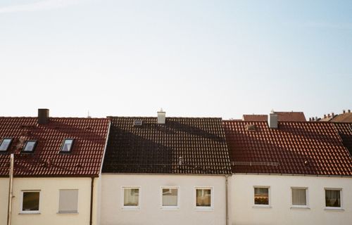 Free Beautiful red and brown tiled rooftops under clear blue sky in suburban area. Stock Photo