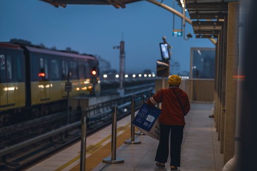 Free A person at an outdoor train station during twilight, holding a large package. Stock Photo