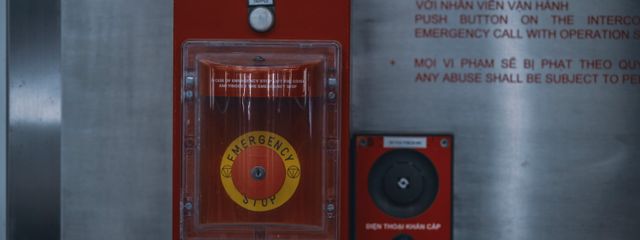 Close-up of an emergency stop button with warning text on an industrial panel.