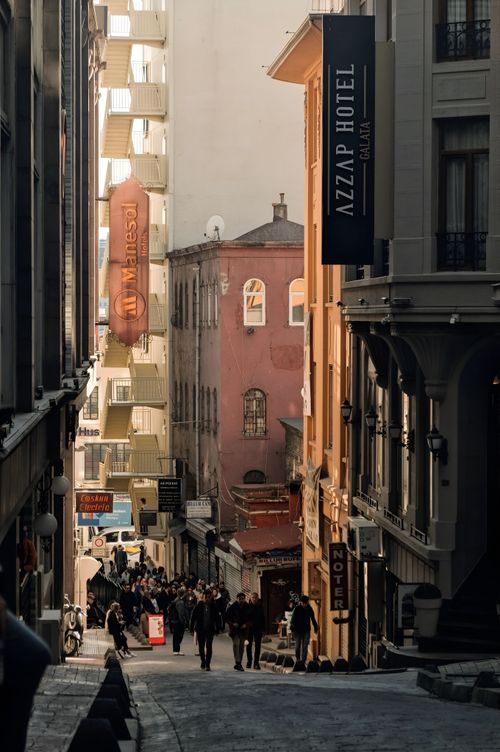 Free Bustling European alley with hotels and a crowd beneath warm sunlight. Stock Photo