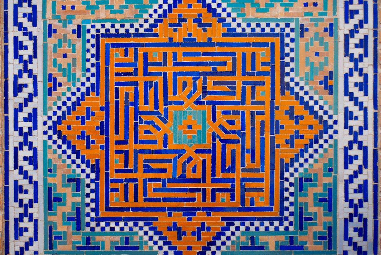Intricate Islamic geometric tile art in vibrant blue, orange, and teal colors.