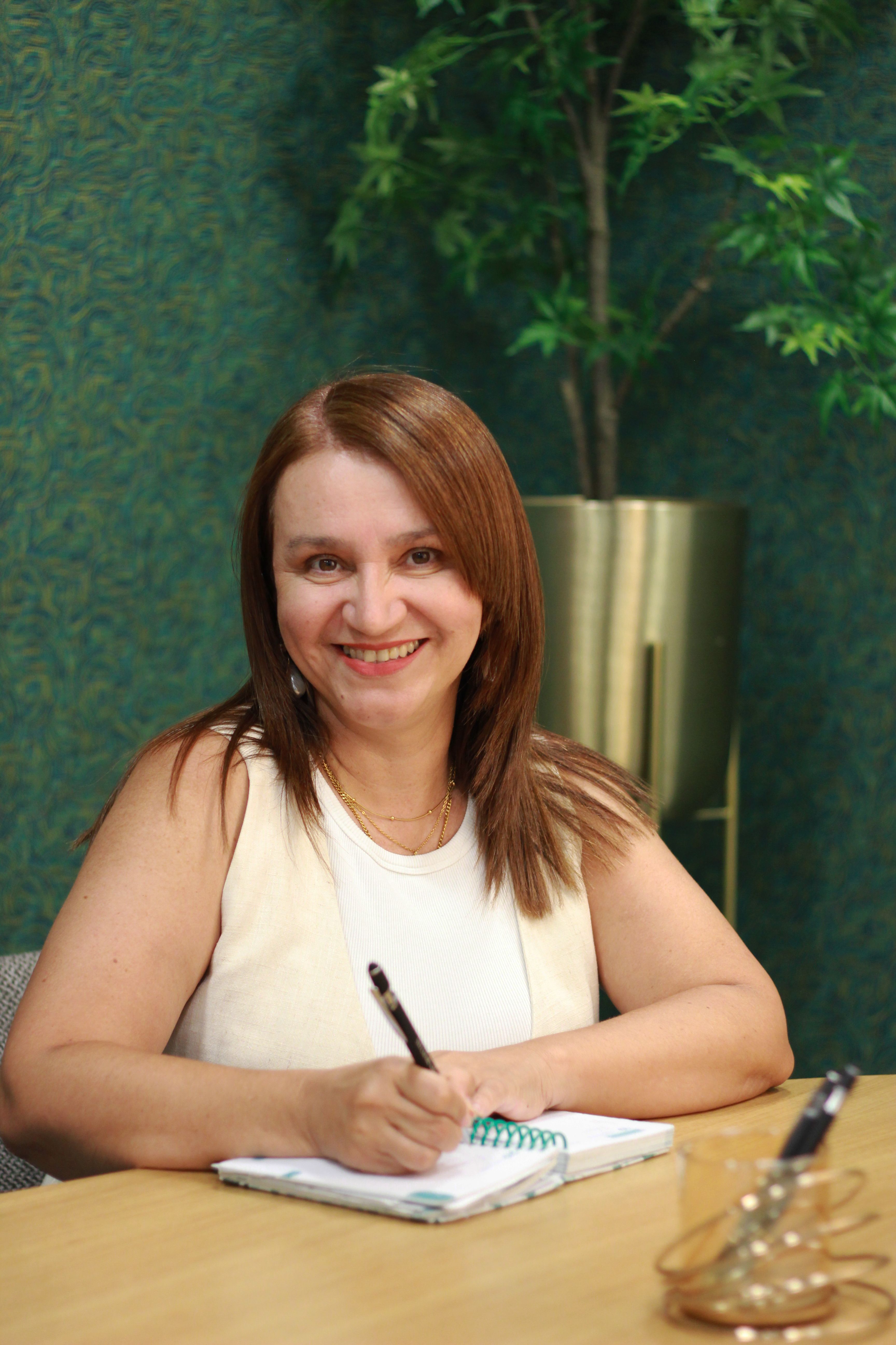 Smiling woman writing notes in a modern office environment in Braga, Portugal.