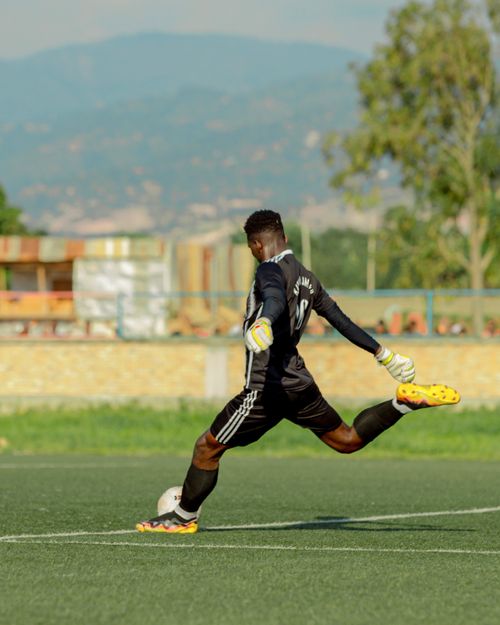 Free A football goalkeeper in action, kicking a ball on a sunny outdoor field. Stock Photo