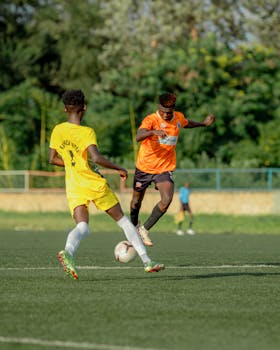 Dynamic image of two soccer players in action during a match on an outdoor field.