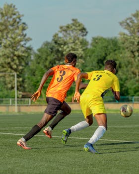 Two soccer players competing fiercely during a game on a bright day outdoors.