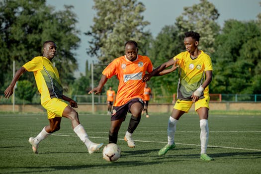 Three players in action during a competitive soccer match on a lush field.