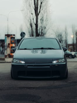 Front view of dark sedan parked on an urban street in a moody, winter setting.