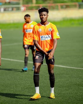 Young soccer players in orange jerseys on a green field, focused and ready for the game.