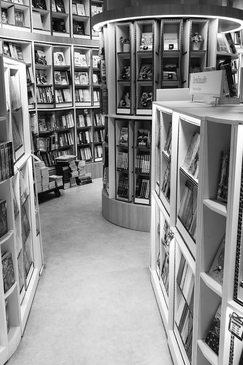 Monochrome view of a bookstore's interior with various bookshelves and romance fiction section.