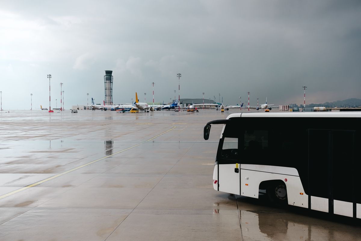 비 내리는 공항 계류장을 가로지르는 승객용 버스