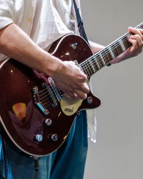 A musician plays an electric guitar during a performance, focusing on the hands.