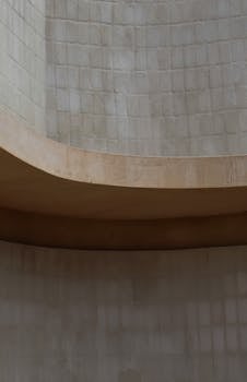 Explore a minimalist architectural design with soft neutral curves and concrete textures.