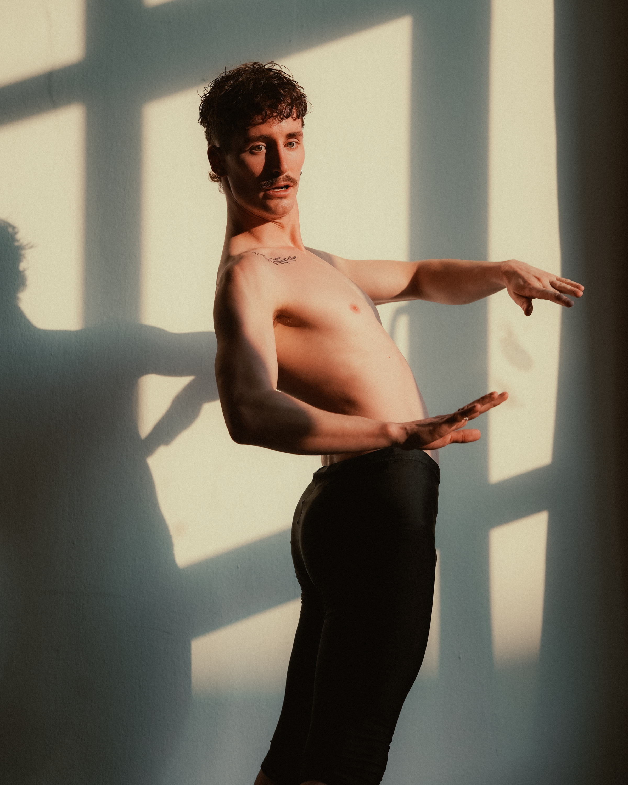 Expressive male dancer poses with dynamic lighting in a studio setting.