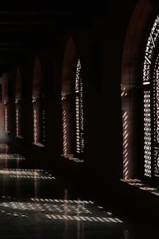 Sunlight casts patterns through ornate arches in an Omani architectural corridor.