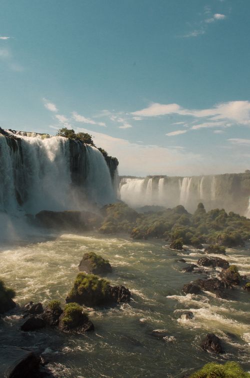 Free Spectacular daylight view of Iguazu Falls cascading into lush greenery and mist. Stock Photo