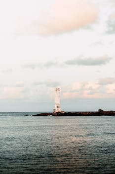 A serene view of a lighthouse on the ocean in Itacaré, Brazil, under calm skies.