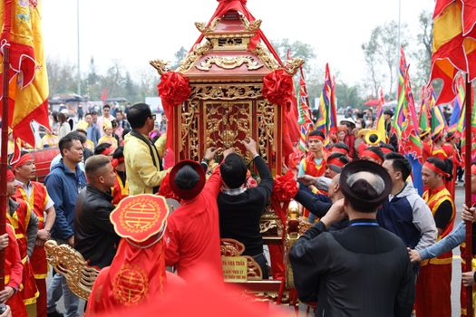Vibrant festival parade with people in traditional attire and colorful flags.