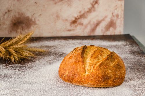 Free Golden artisan bread on a flour-dusted surface in a rustic setting. Stock Photo