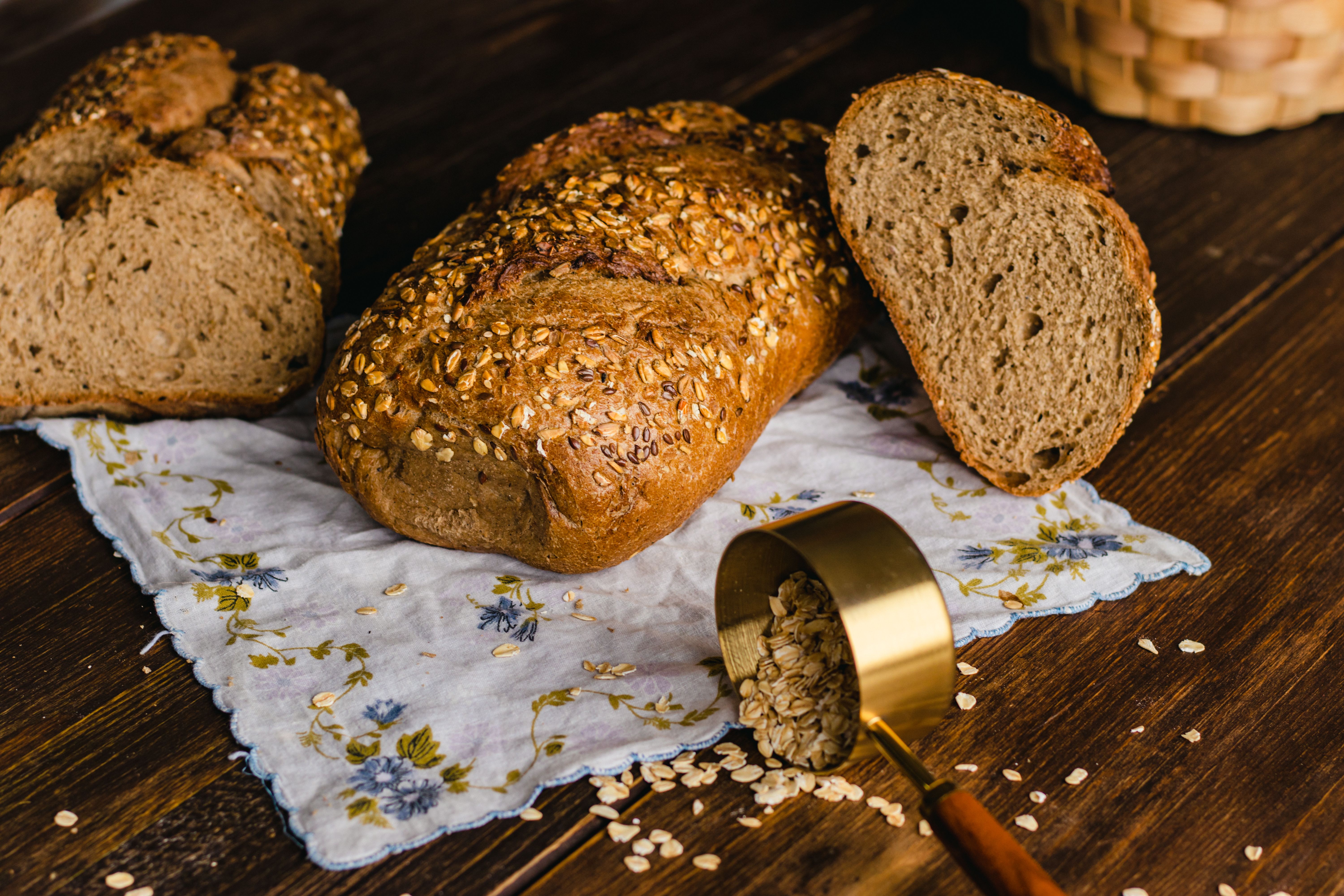 Rustic Whole Grain Bread Loaf on Floral Cloth · Free Stock Photo