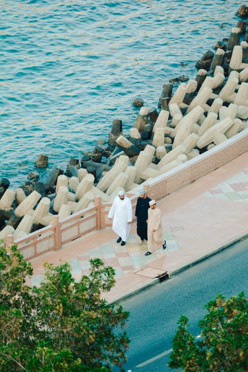 Free Aerial shot of three people walking along the Omani coast by the sea with distinctive geometric barriers. Stock Photo