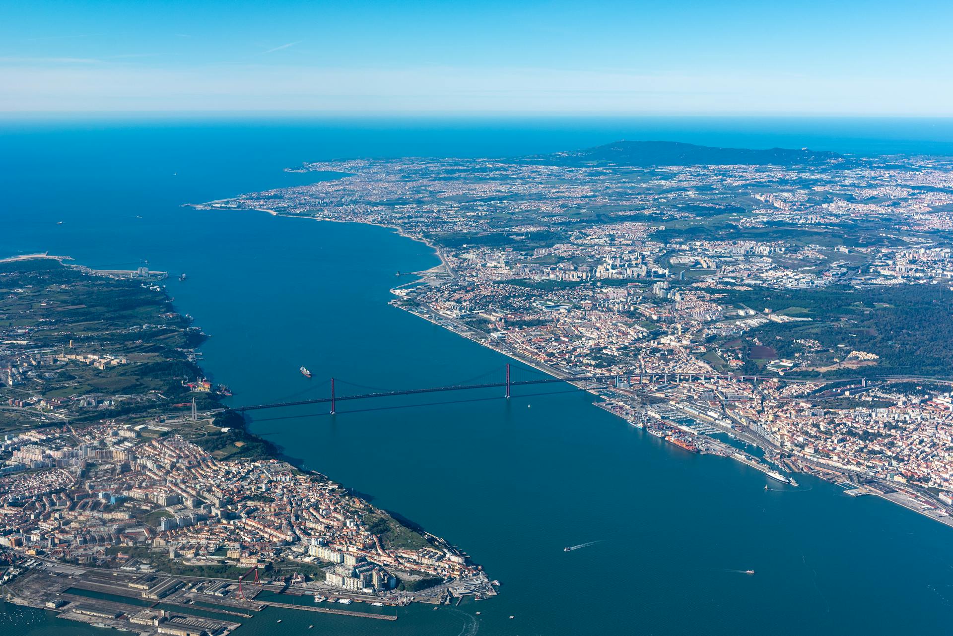 Explore the stunning aerial view of Lisbon featuring the iconic 25 de Abril Bridge spanning the Tagus River.