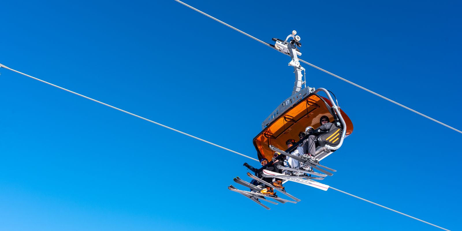 A ski lift carrying skiers beneath a clear blue winter sky