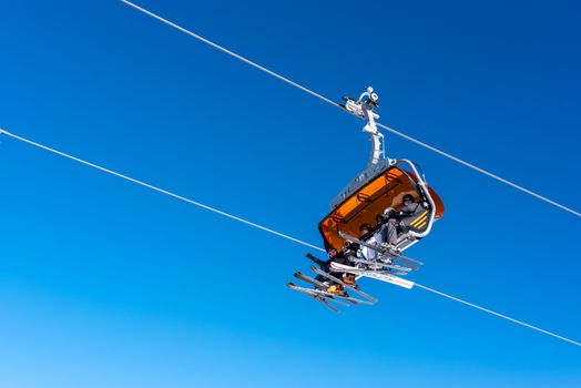 Ski lift carrying skiers against a clear blue sky in Białka Tatrzańska, Poland.