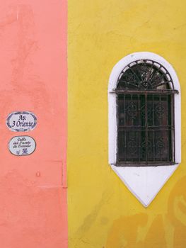 Colorful colonial-style window in Puebla, Mexico, showcasing a blend of vibrant pink and yellow walls.