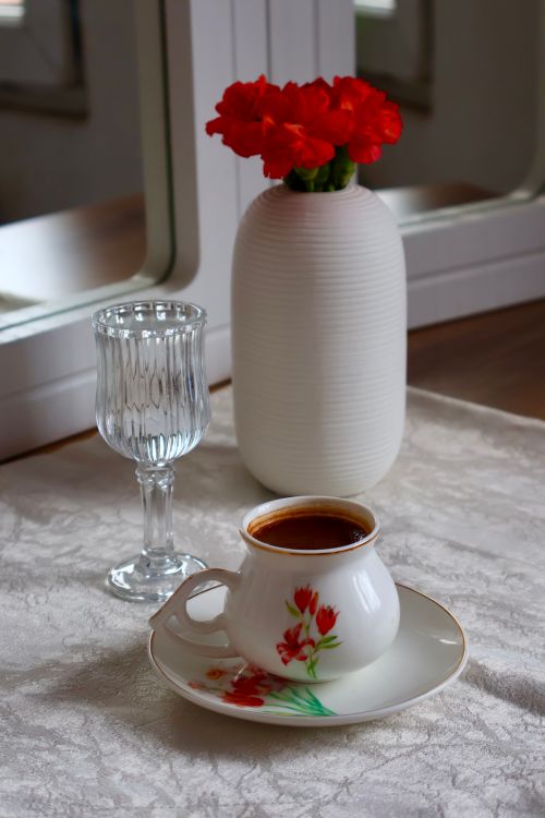 Free Chic table setting with coffee, red flowers, and a crystal glass. Stock Photo