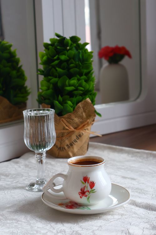 Free Cozy indoor scene with coffee, glass, and lush green plant. Stock Photo